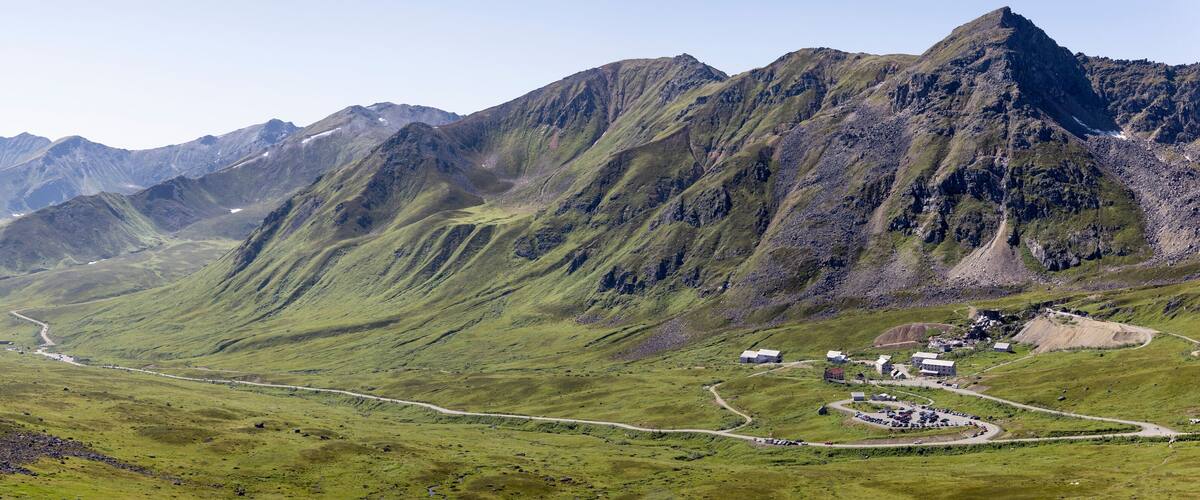 Independence Mine State Historical Park Visitor Center surrounded by the Talkeetna Mountains across Hatcher Pass under a sunny, blue sky; Palmer, Alaska, United States of America