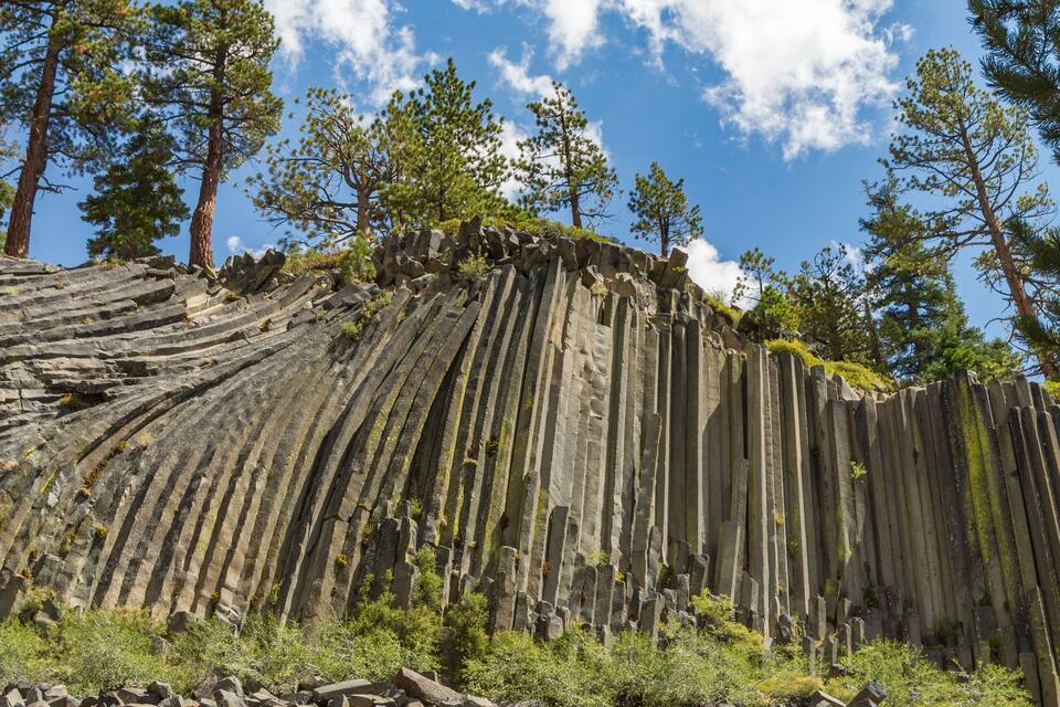 A rocky terrain with layered rock formations and scattered trees under a clear sky.