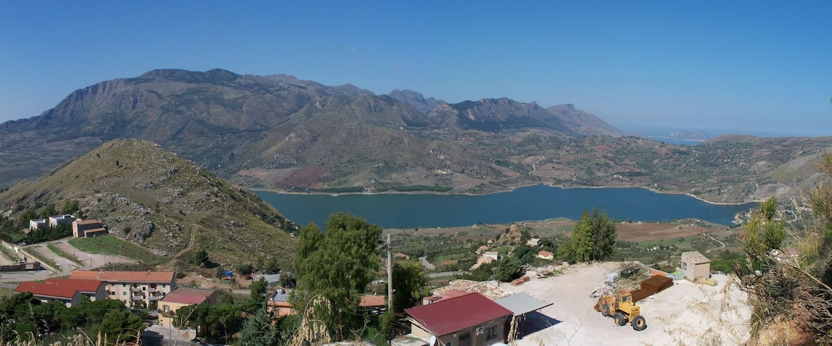 A mountainous landscape with a lake, a small settlement, and a clear sky.