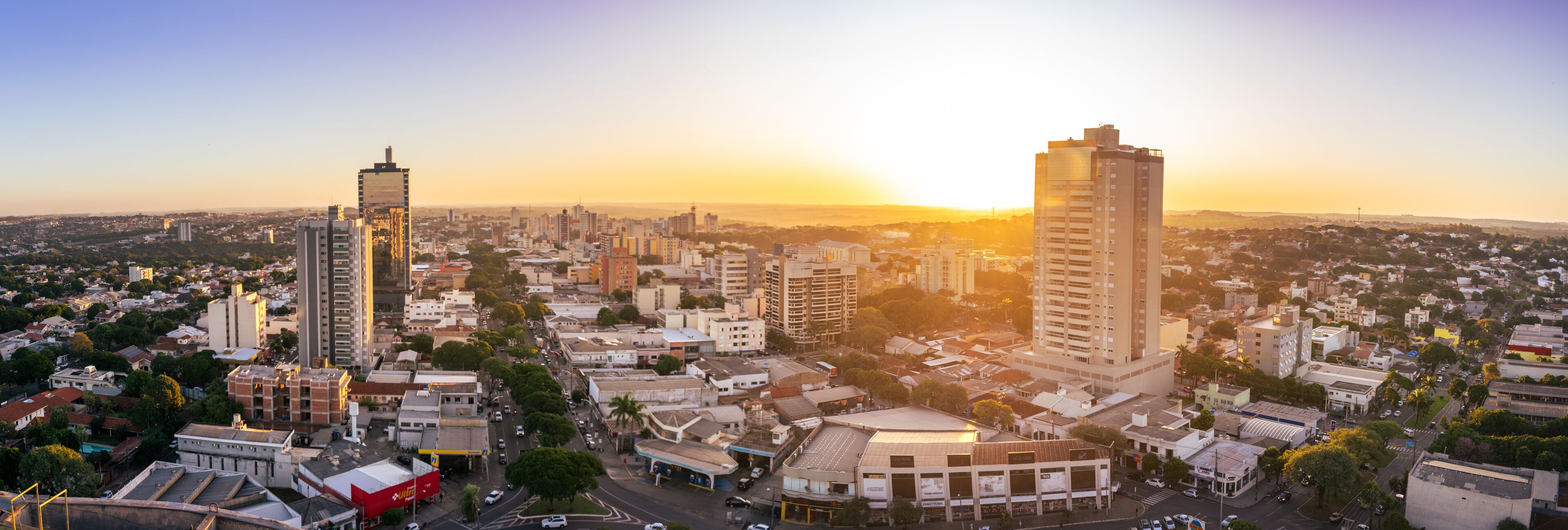 A cityscape with tall buildings, a prominent red building, and a sunset.