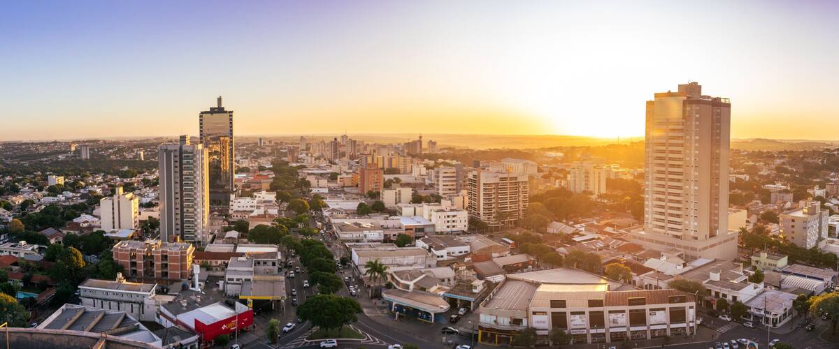 A cityscape with tall buildings, a prominent red building, and a sunset.