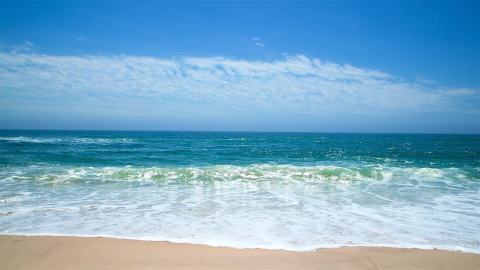 A beach with waves and a clear blue sky.
