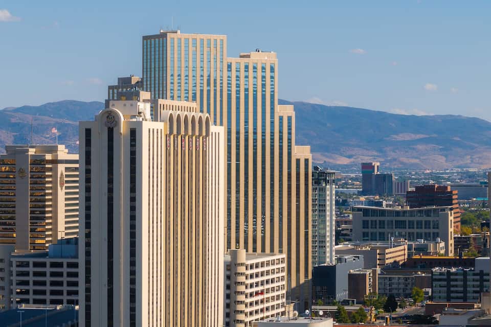 A cityscape with tall buildings, a large spherical structure, and mountains in the background.