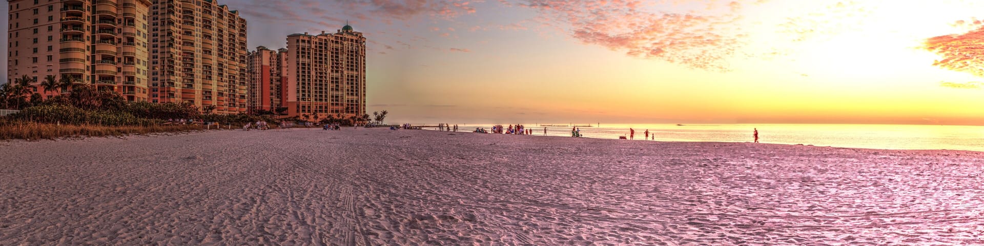 A beach with high-rise buildings and a sunset.