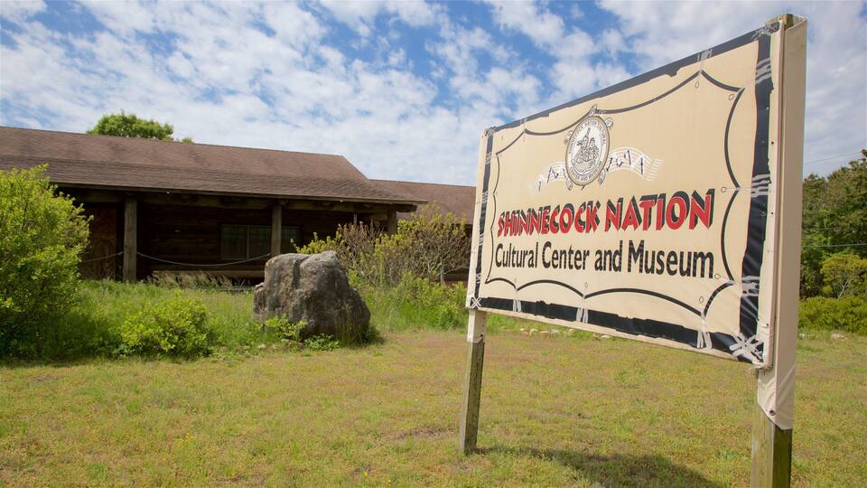 A sign for the Shinnecock Nation Cultural Center and Museum with a wooden building in the background.