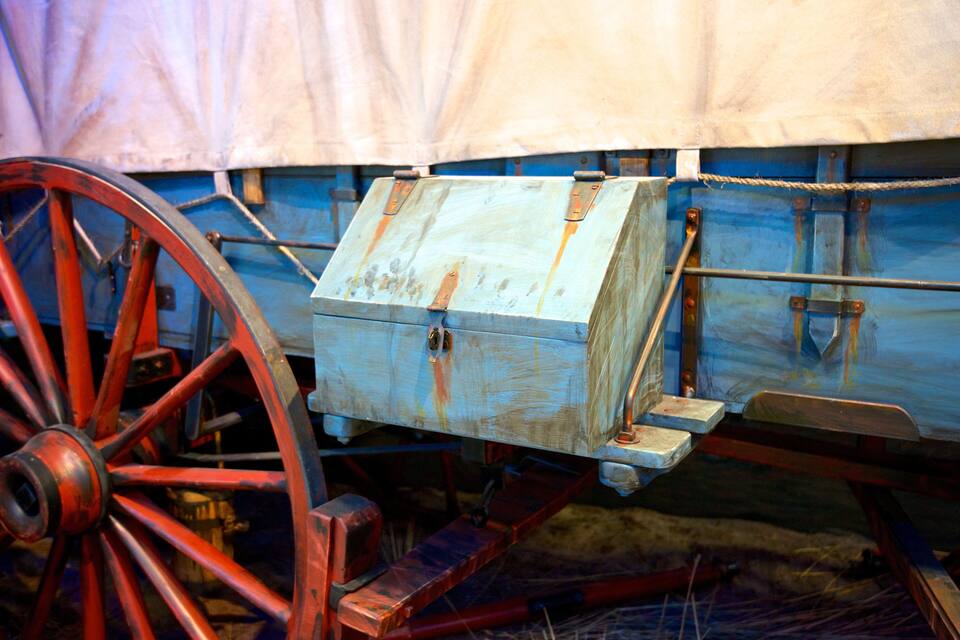 A vintage wooden cart with a metal frame and red wheels.