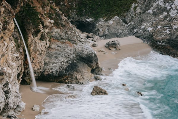 McWay Falls featuring rugged coastline, a waterfall and a sandy beach
