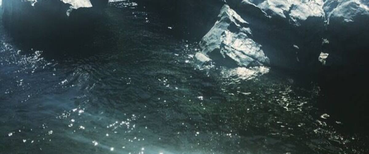 A body of water reflecting sunlight, surrounded by rocky terrain.