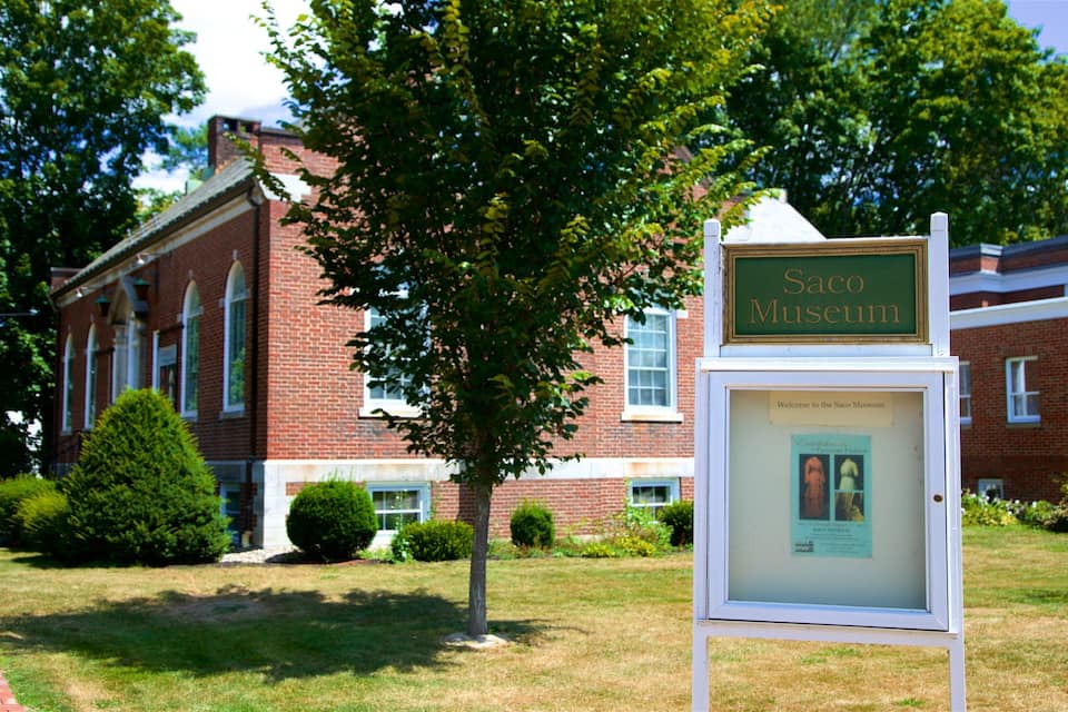Une enseigne indiquant le musée de Saco, devant un bâtiment en briques.