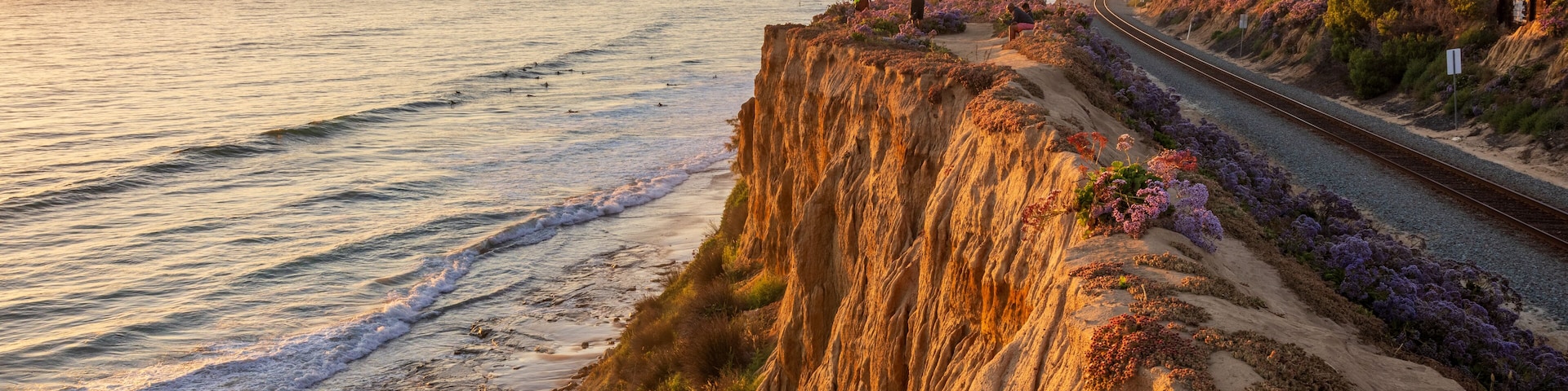 A coastal landscape with a cliff, beach, and a railway track.