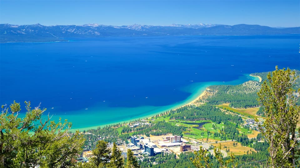 A coastal town with a clear blue lake, a sandy beach, and a forested area.