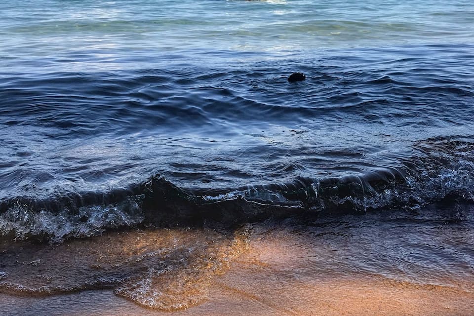 Un bateau sur une eau calme, avec des vagues qui se rapprochent du rivage.