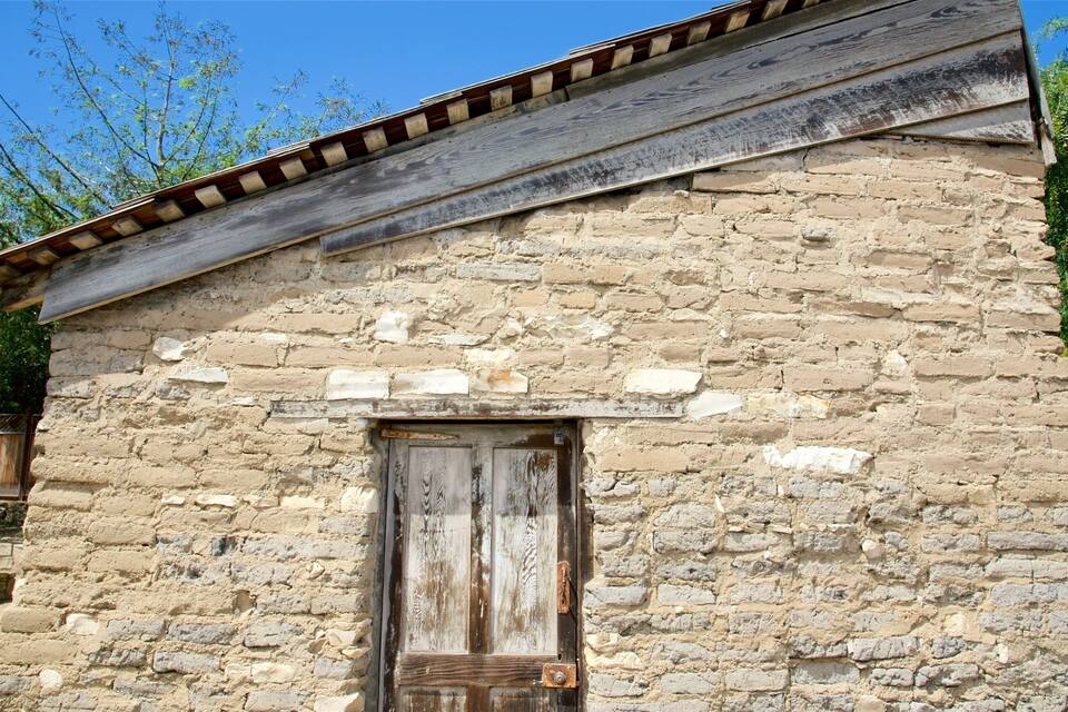 A rustic stone building with a wooden door and a sloped roof.
