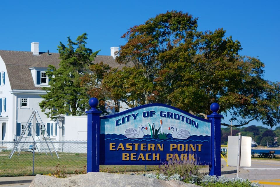 A sign for City of Groton Eastern Point Beach Park with a white house in the background.