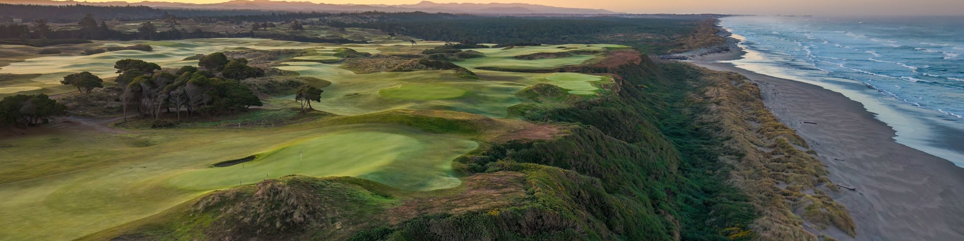 A coastal golf course with a beach and ocean.