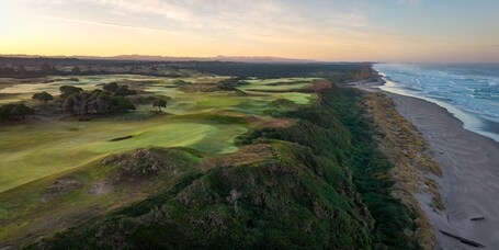 A coastal golf course with a beach and ocean.
