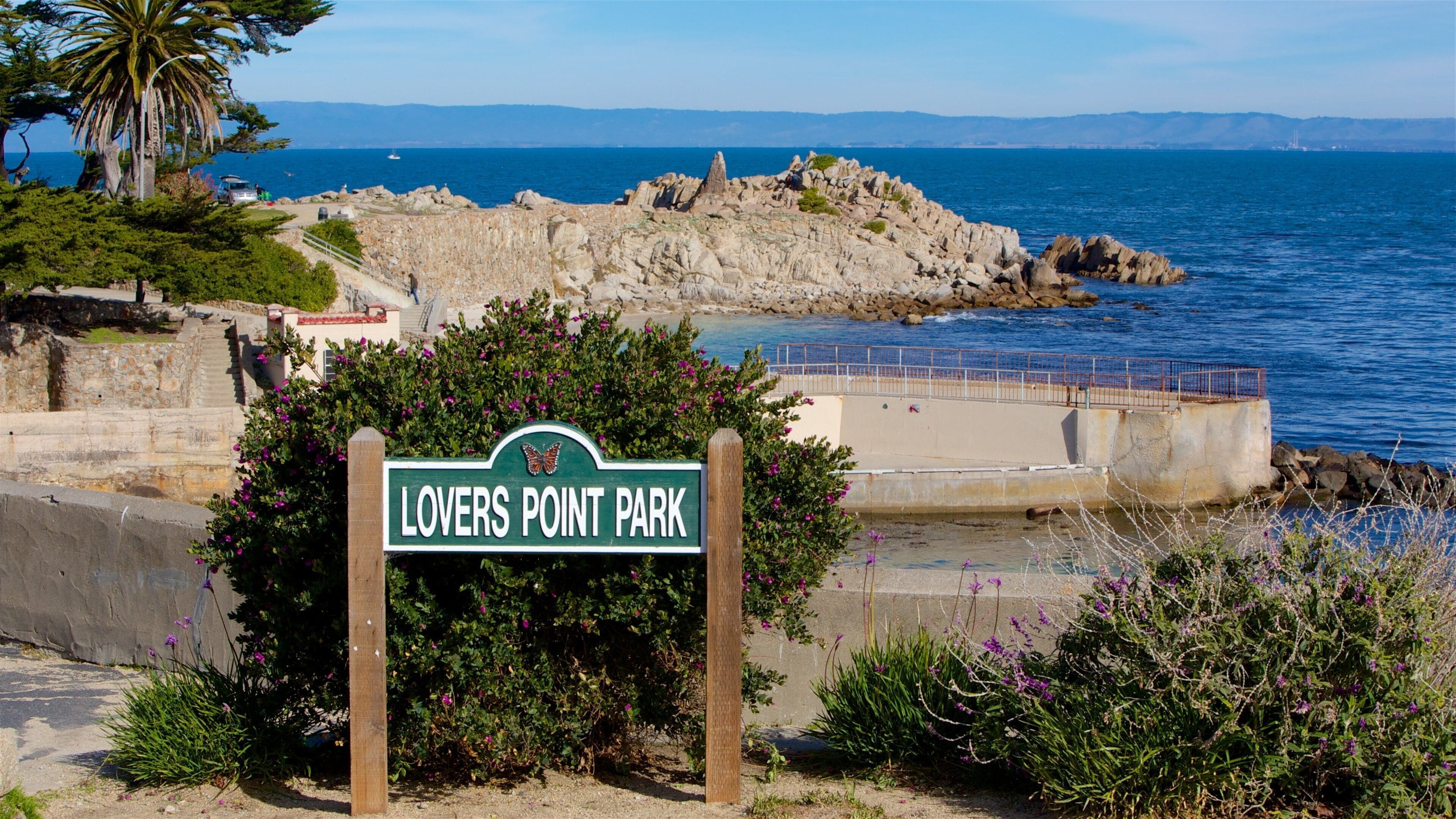 Señal para el Parque Lovers Point con vistas al océano y a la costa rocosa.