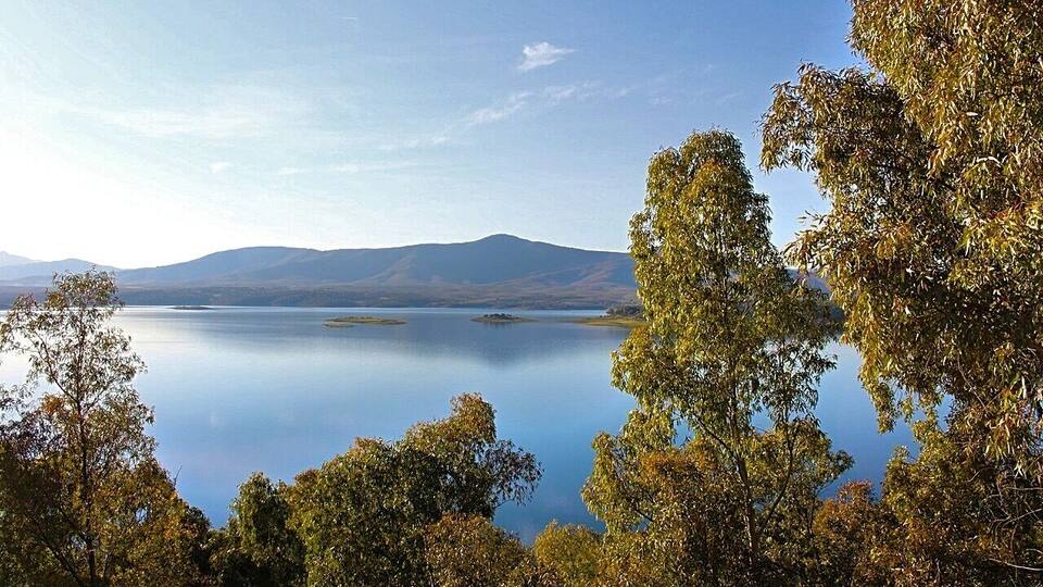 A calm lake surrounded by trees and mountains.