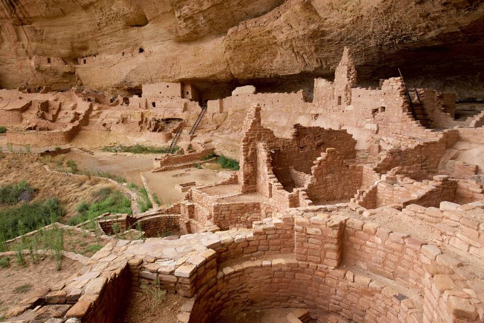 Ancient cliff dwellings with multiple levels and structures built into the rock face.
