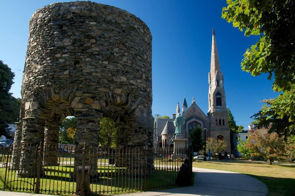 A stone tower, a church with a tall spire, and a clear blue sky.