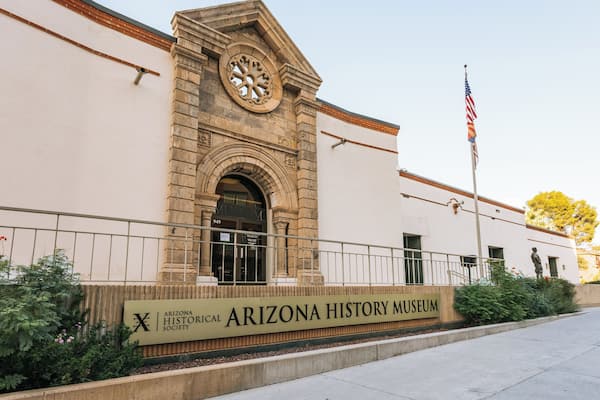 The Arizona History Museum with a prominent clock tower, an American flag, and a signboard.
