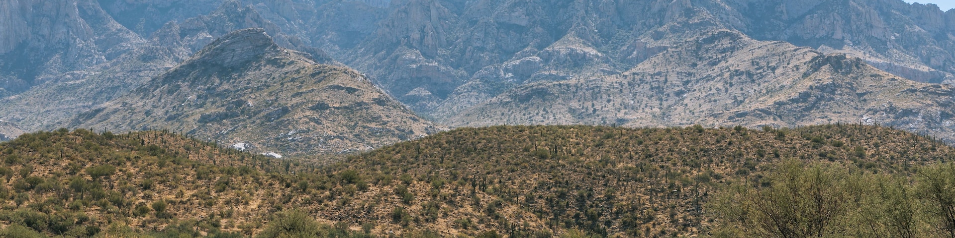 Paisagem montanhosa com vegetação rala e grama seca.