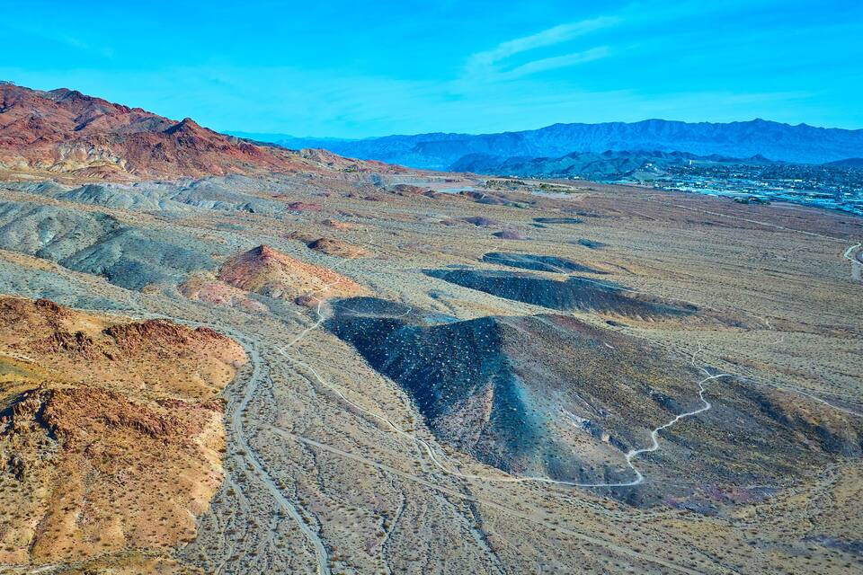 A rugged mountainous landscape with winding roads and a distant town.