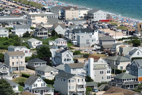 Área residencial costeira com casas, praia e estacionamento.