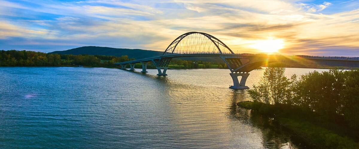 Bridge at sunset with blue skies over water connecting New York to Vermont