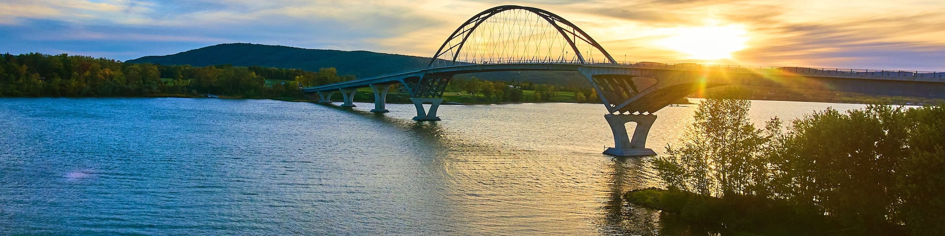 Bridge at sunset with blue skies over water connecting New York to Vermont