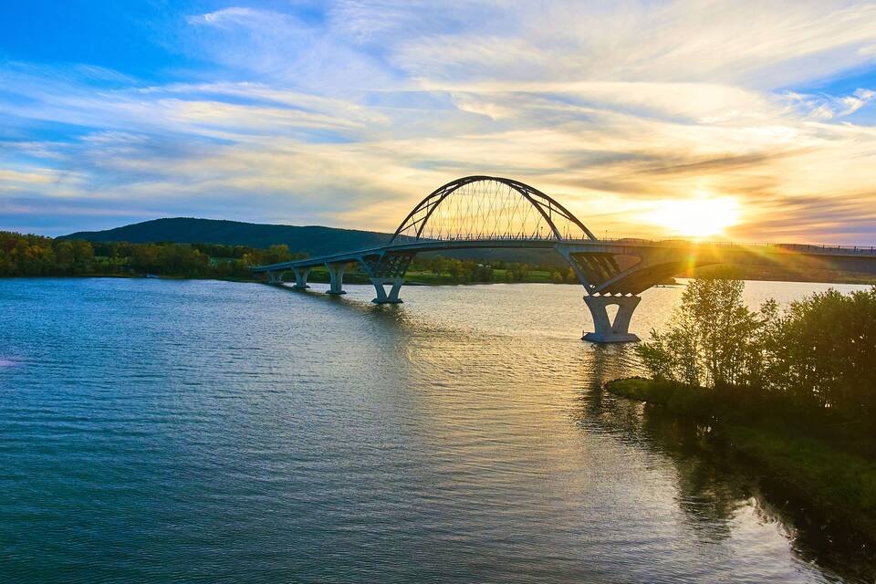 Un puente sobre un río con un atardecer de fondo.