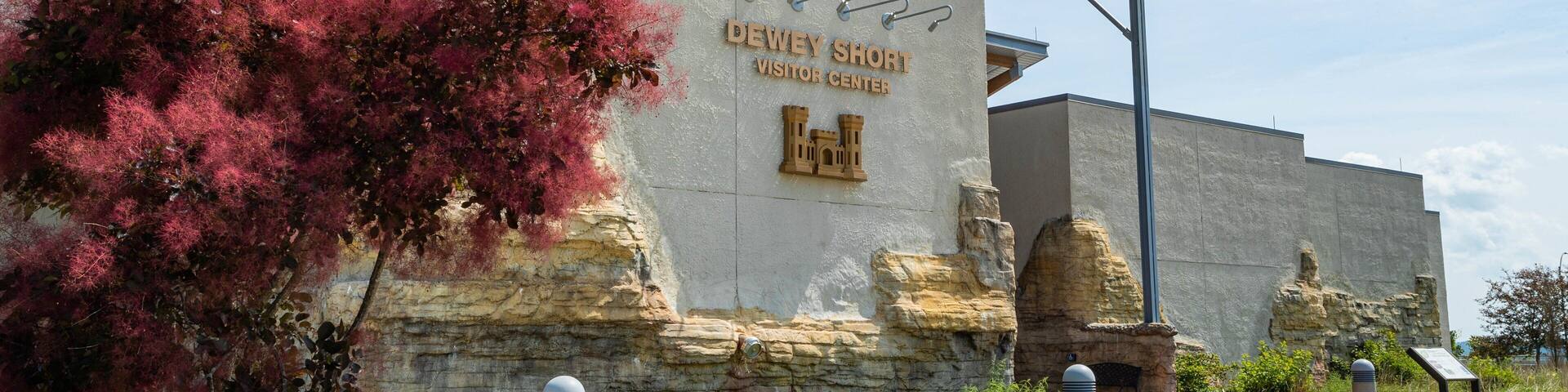 The Dewey Short Visitor Center with a stone facade, a covered entrance, and a sign.