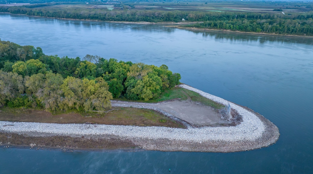 An aerial view of a river with a small island covered in trees and a rocky shoreline.