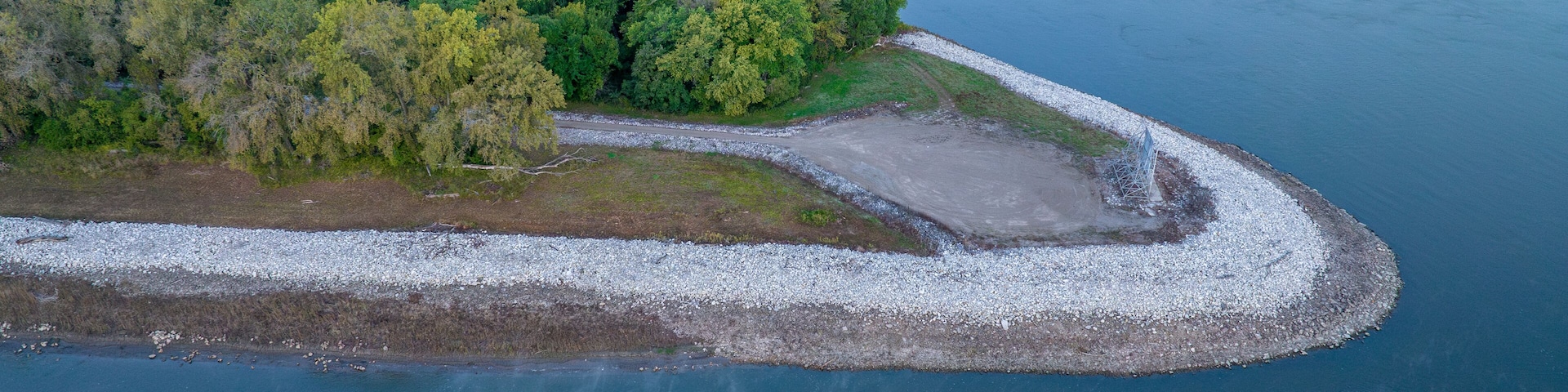 Vista aérea de un río con una pequeña isla cubierta de árboles y una orilla rocosa.