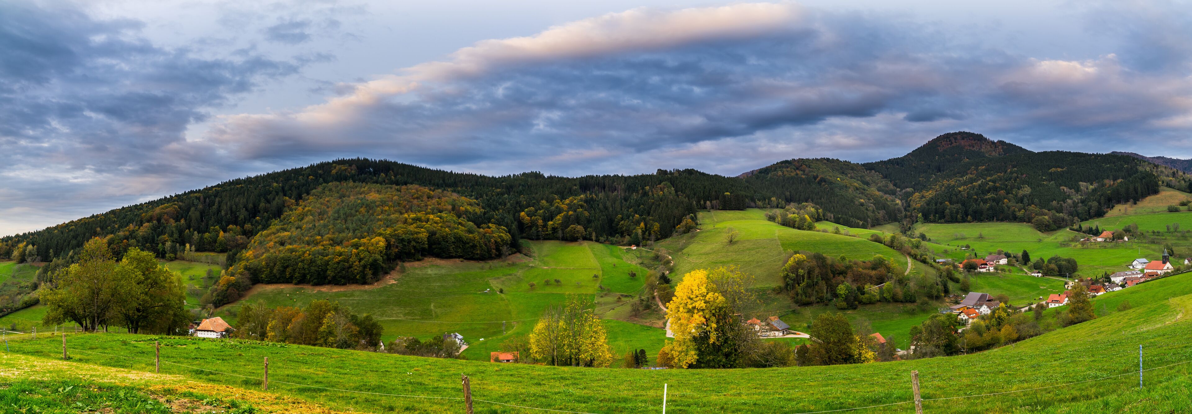 Germany, XXL panorama of black forest village elzach houses and church in idyllic valley surrounded by colorful nature landscape in autumn season at sunset
