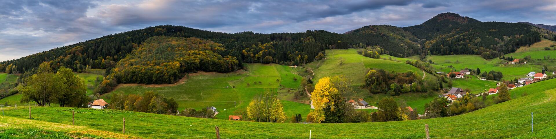 Germany, XXL panorama of black forest village elzach houses and church in idyllic valley surrounded by colorful nature landscape in autumn season at sunset