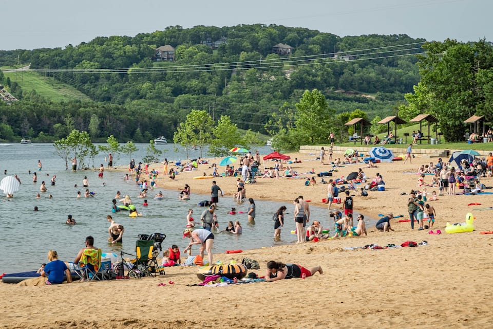 A crowded beach with people swimming and sunbathing.