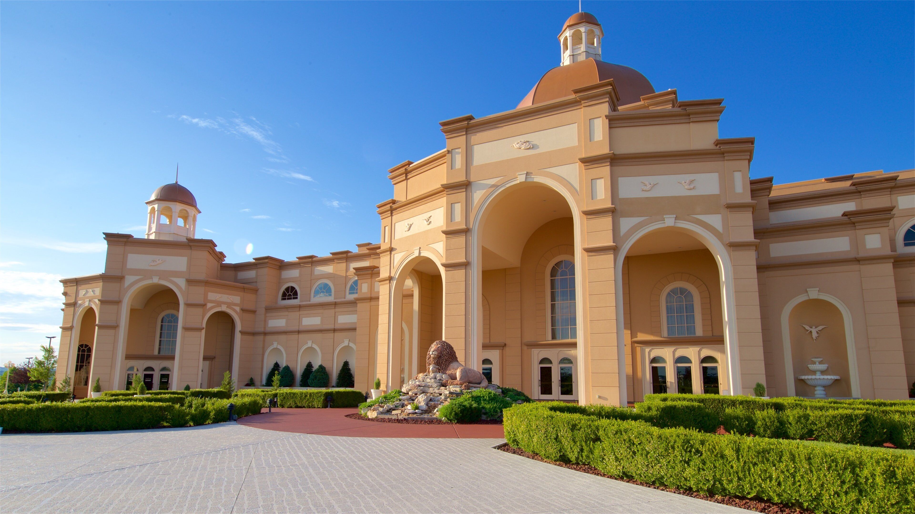 A grand building with domed towers, arched walkways, and a well-manicured garden.