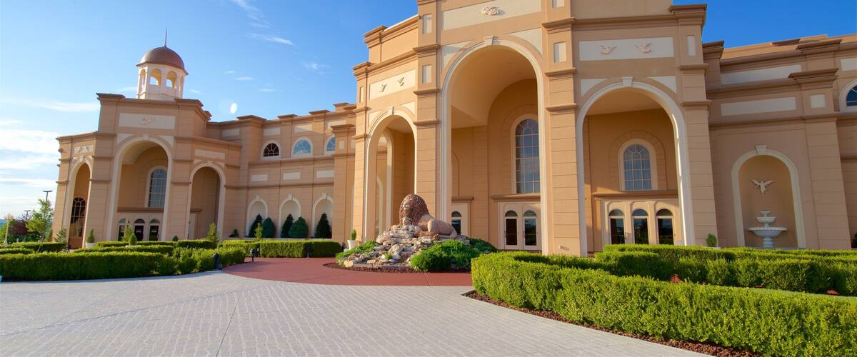 A grand building with domed towers, arched walkways, and a well-manicured garden.