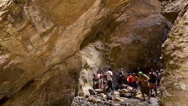 Zapata Falls showing a gorge or canyon as well as a small group of people