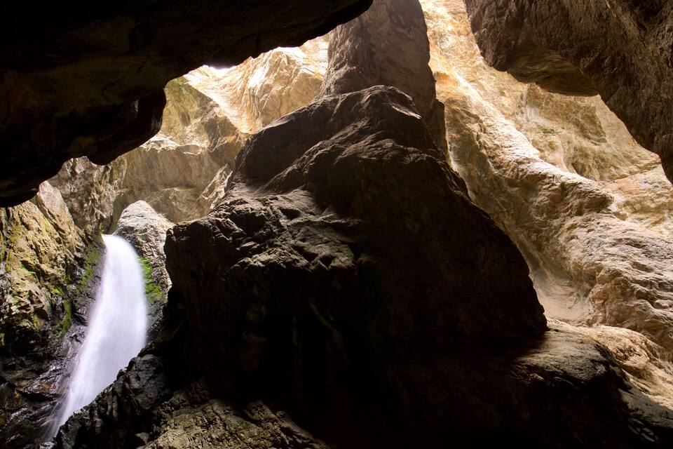 A cave with a waterfall and rugged rock formations.