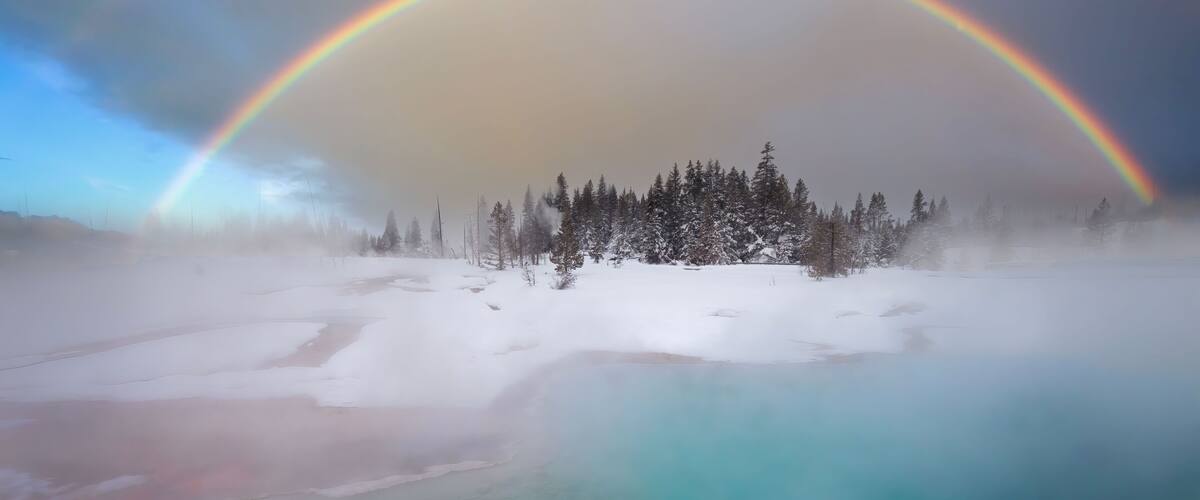 Double Rainbow over steaming hot spring in snowy landscape