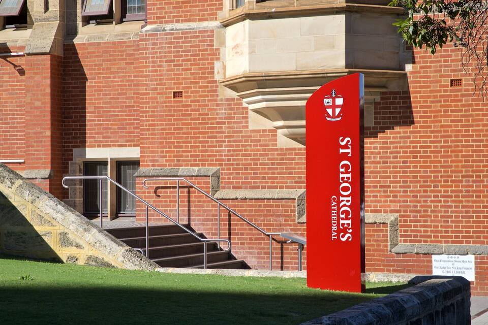 A red banner with 'St George's Cathedral' written on it, a set of stairs, and a brick building.