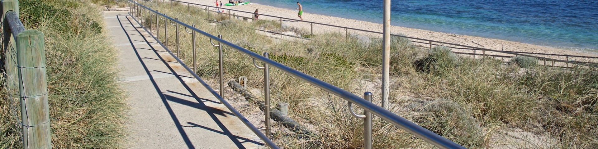 A coastal walkway with a sign indicating general warnings and life-saving services.