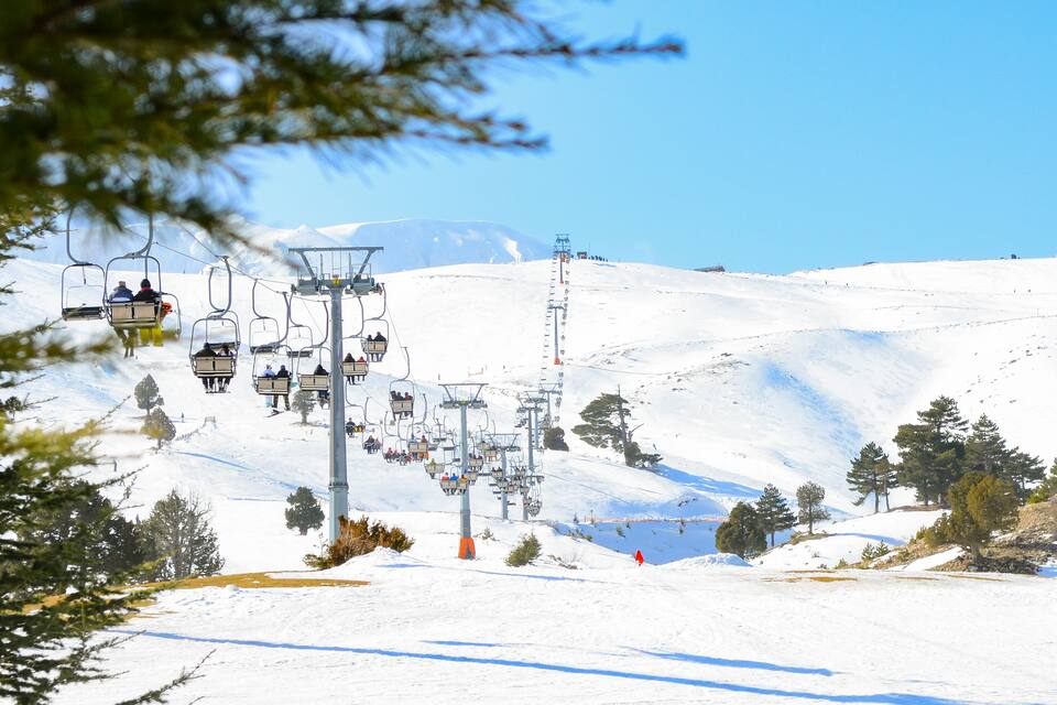 A ski lift on a snowy mountain with clear skies.