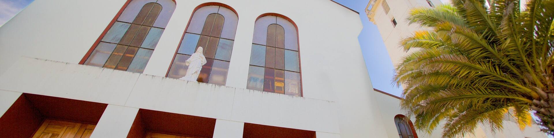 A white church with three arched windows and a cross above the central window.