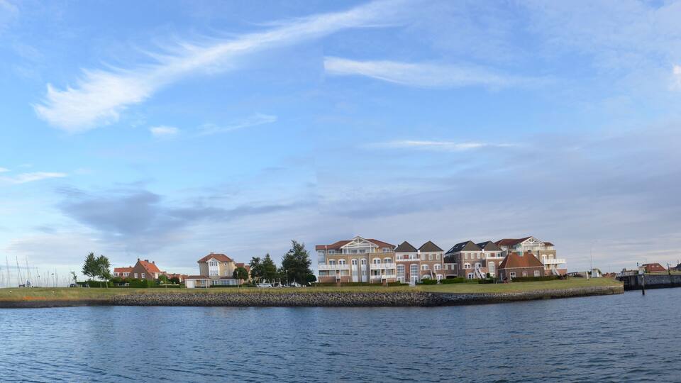 A waterfront with a row of houses and a marina with sailboats.