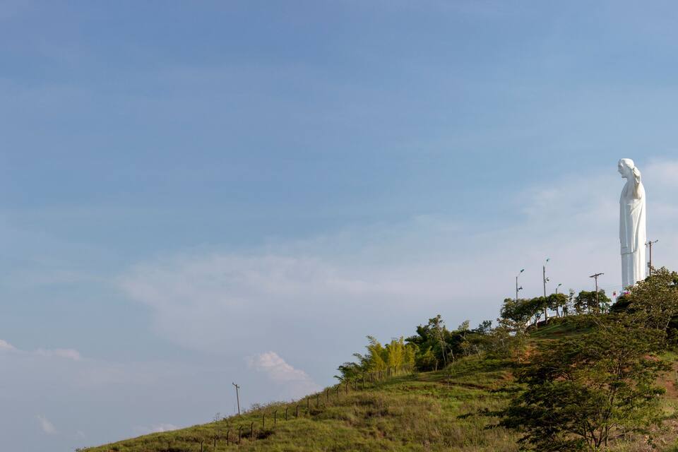 Une statue blanche sur une colline verdoyante, sous un ciel dégagé.