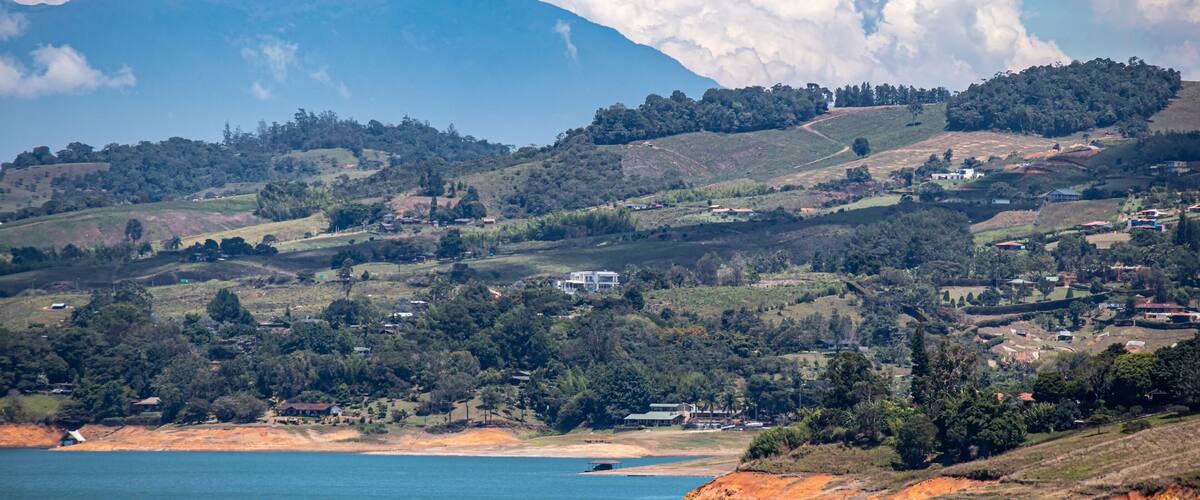 A coastal landscape with a mountain in the background, a beach, and scattered houses.