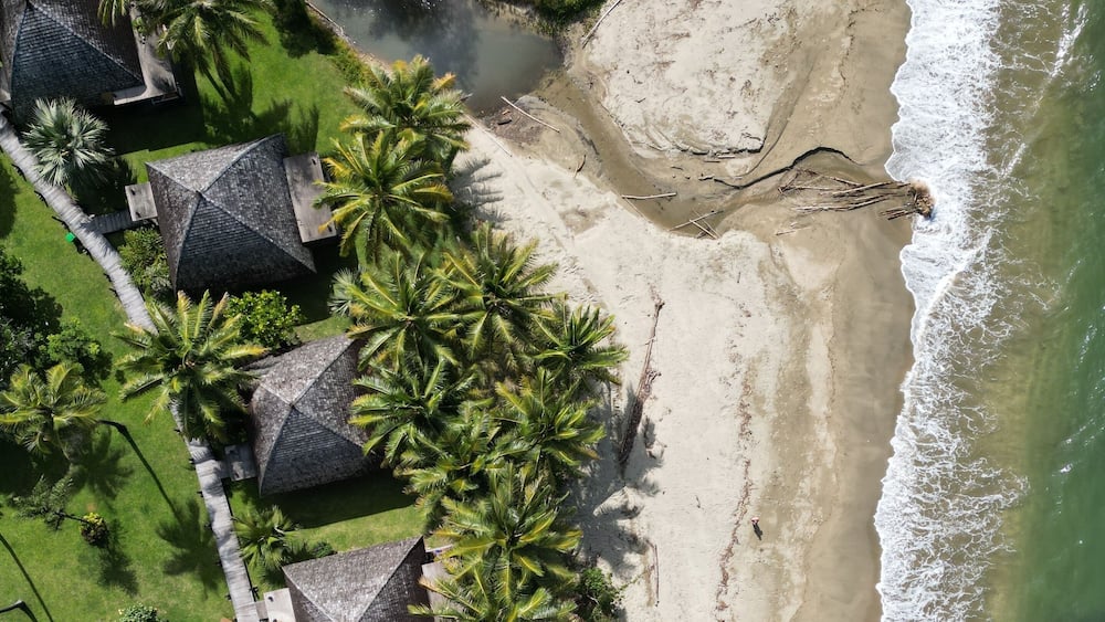 Aerial top view shot of a Poindimie beach river with houses in New Caledonia